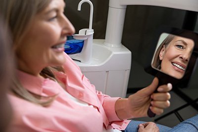 Happy patient looking at her smile in mirror